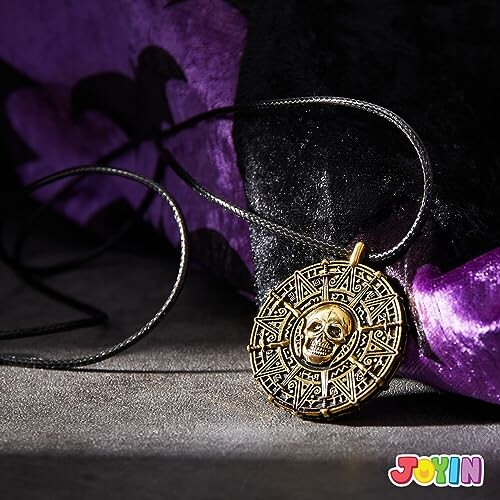 Gold pirate skull medallion necklace on black and purple fabric.